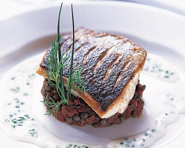 Sea bass with lentils on a white plate