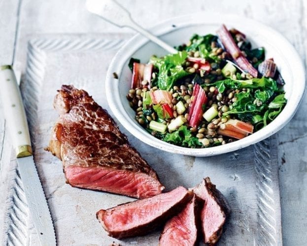 Seared sirloin steak shown sliced with a bowl of lentil salad on the side