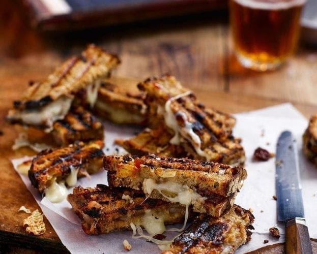 Gooey griddled taleggio and chutney toastie fingers on a serving plate.