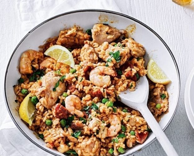 Chicken, prawn and chorizo paella shown in a white pan