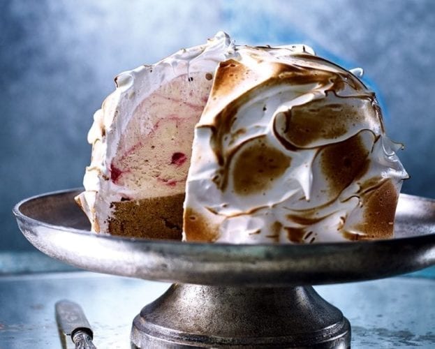 Almond sponge and raspberry ripple baked alaska on a cake stand
