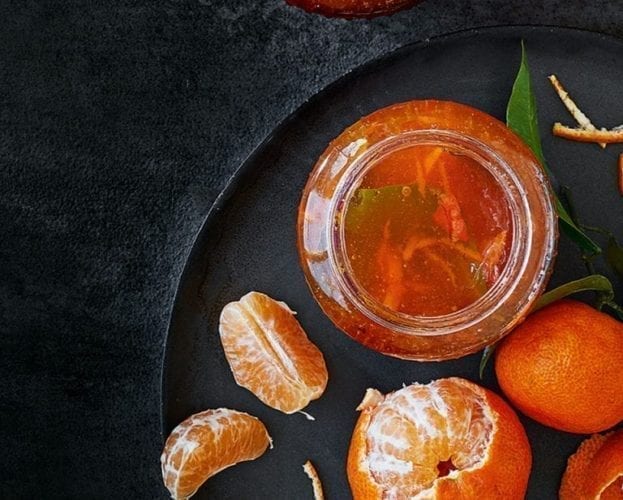 Clementine marmalade shown in glass jars on a black background