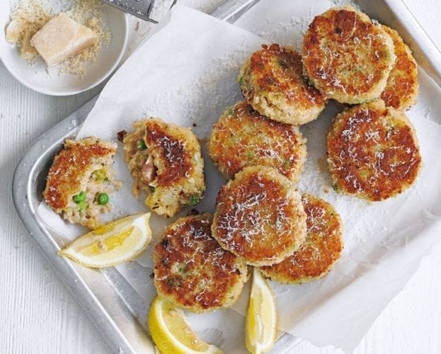 Arancini cakes shown on a silver tray, with lemon slices