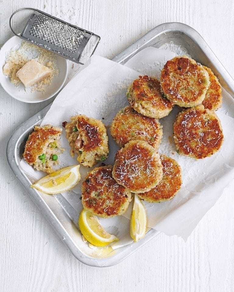 Arancini cakes shown on a silver tray, with lemon slices