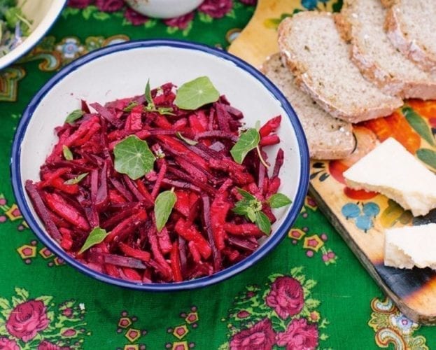 Beetroot and apple pickle shown in a bowl on a bright green background