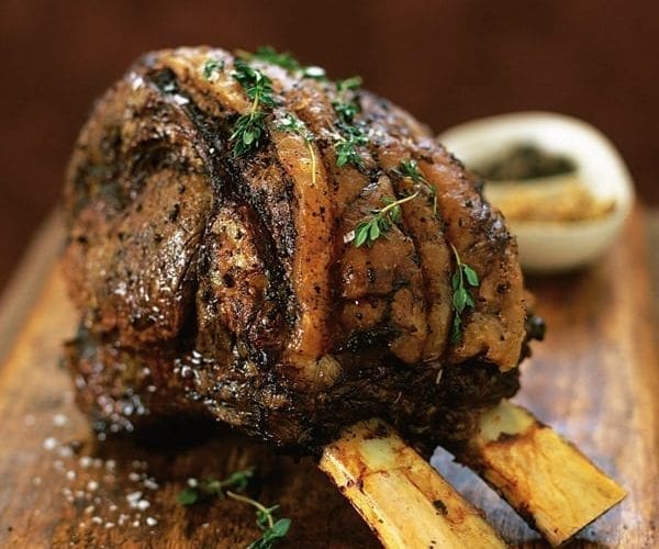 Roasted rib of beef shown on a wooden board