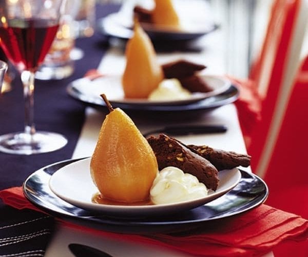 Pear puddings shown on plates on a neatly-set table