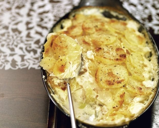 Potato, celeriac and apple gratin shown in a black dish