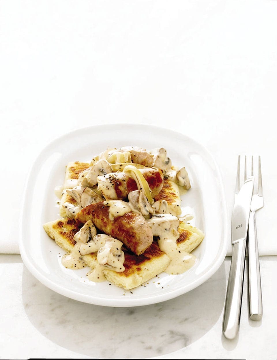 Quick sausages in white wine sauce on potato cakes recipe | delicious. magazine