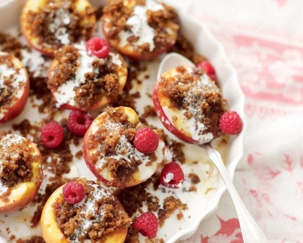 Rum-soaked baked peaches with Jamaican ginger cake pudding in a white bowl