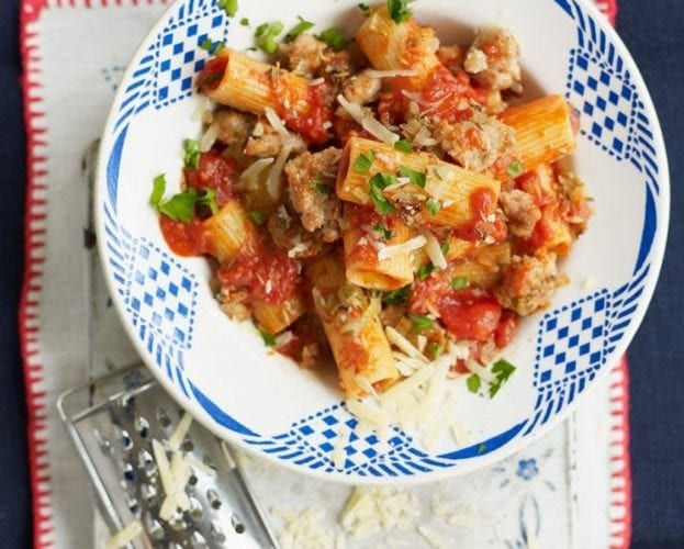 Rigatoni with sausage and fennel ragu in a blue and white bowl.