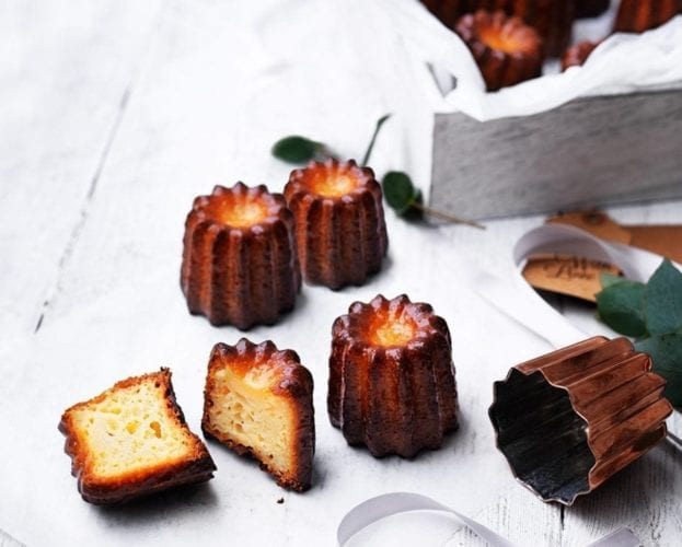 Caneles shown on a table, with one sliced in half
