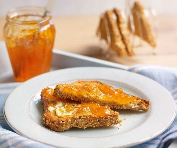 Apricot jam spread on toast, on a white plate