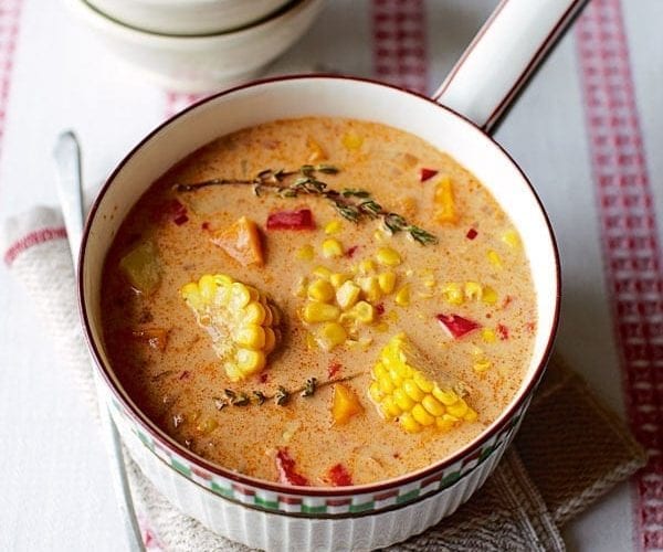 Sweetcorn cobs in a Jamaican corn soup, in a white saucepan