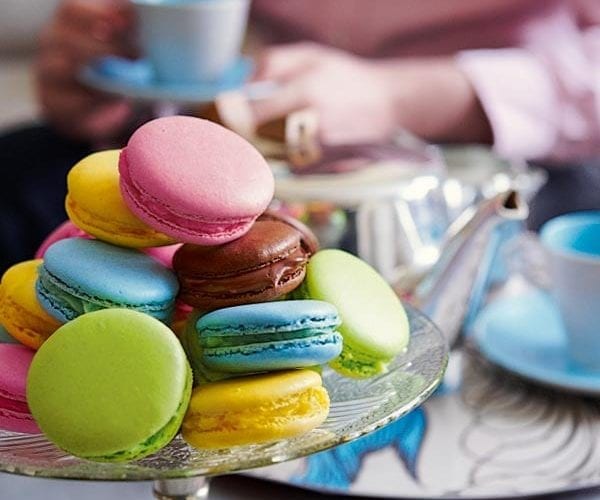 Colourful macarons in blue, pink, yellow and green on a glass cake stand