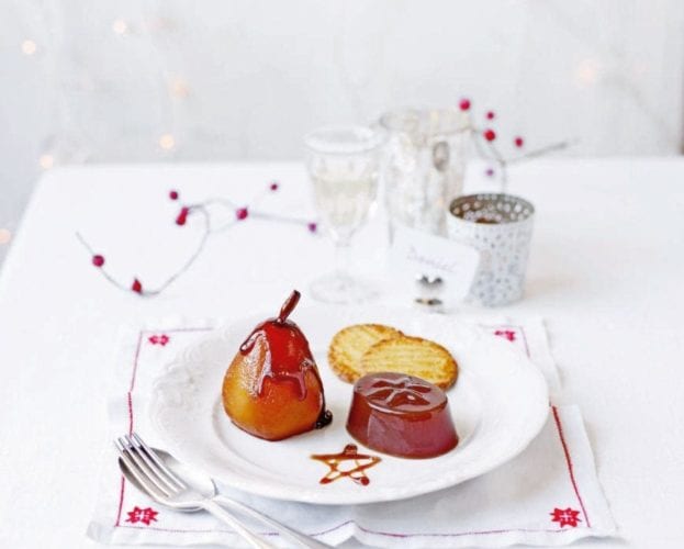A poached pear shown next to an individual jelly on a white festive table