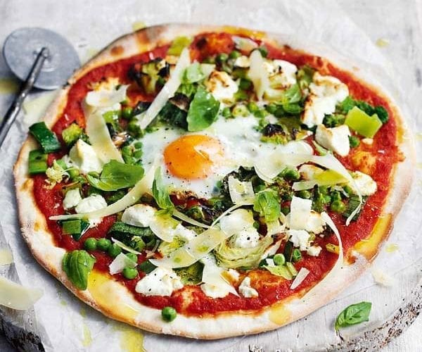 Pizza topped with a cooked egg and green veg