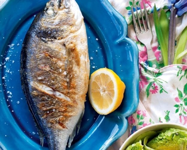 Griddle whole black bream fish shown on a blue plate