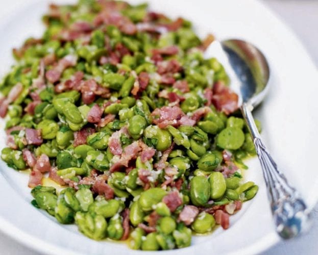 Warm broad bean and bacon salad shown on a white plate
