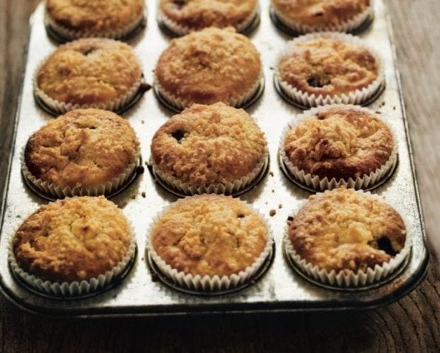 Baked blackberry and apple muffins shown in their cases in a muffin tray