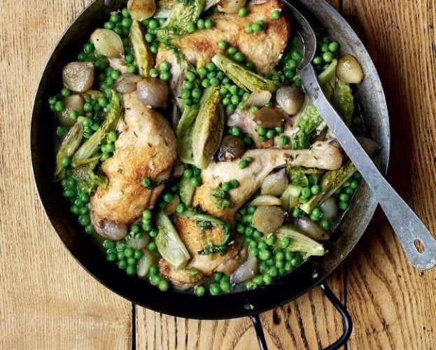Braised chicken legs with onions, lettuce and peas in a black pan
