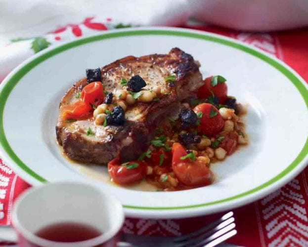 Pork chop served with beans on a white plate