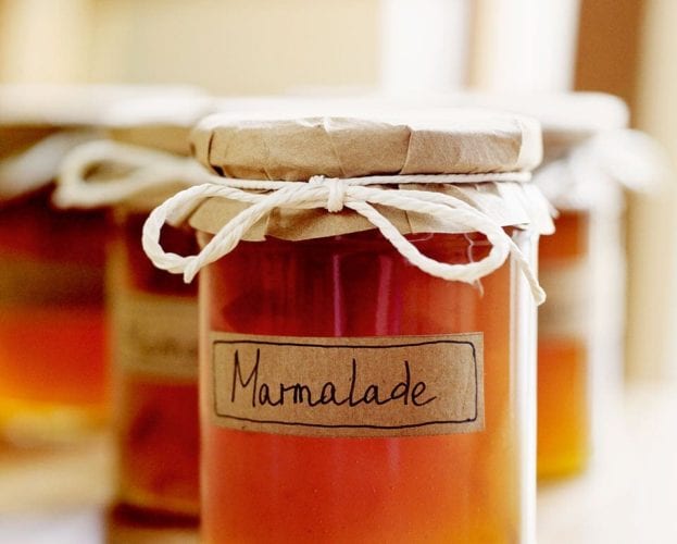 A jar of marmalade with a hand-written label and fabric lid