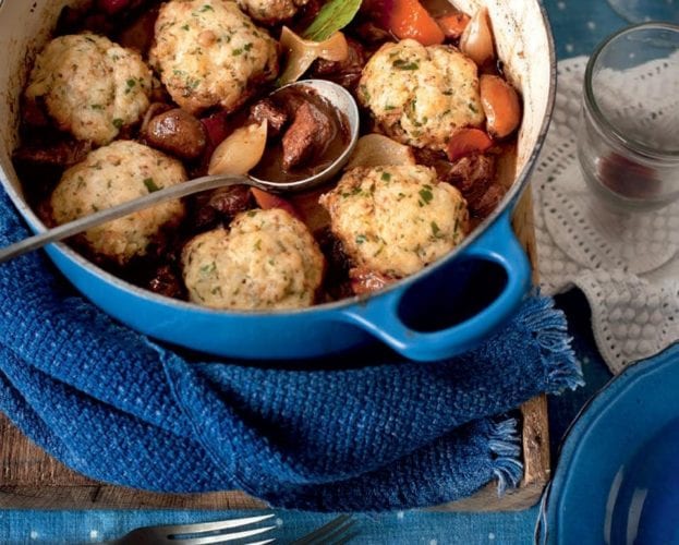 Beef stew topped with dumplings, shown in a blue casserole