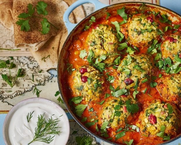 Lamb meatballs shown in a bright red sauce in a blue casserole dish