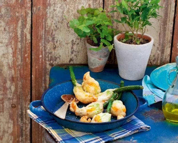 Fried courgette flowers shown on a plate in a garden