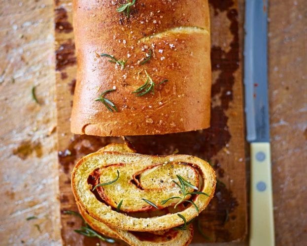 A loaf of stromboli bread shown with a slice cut out to show the spiral inside