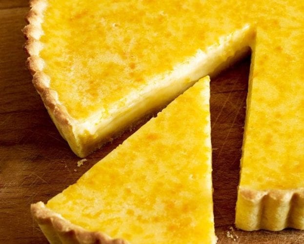 A cooked Seville orange tart shown with a triangle slice taken out