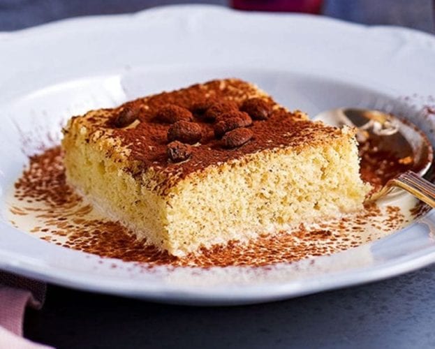 A slice of tres leches cake sitting on a white plate