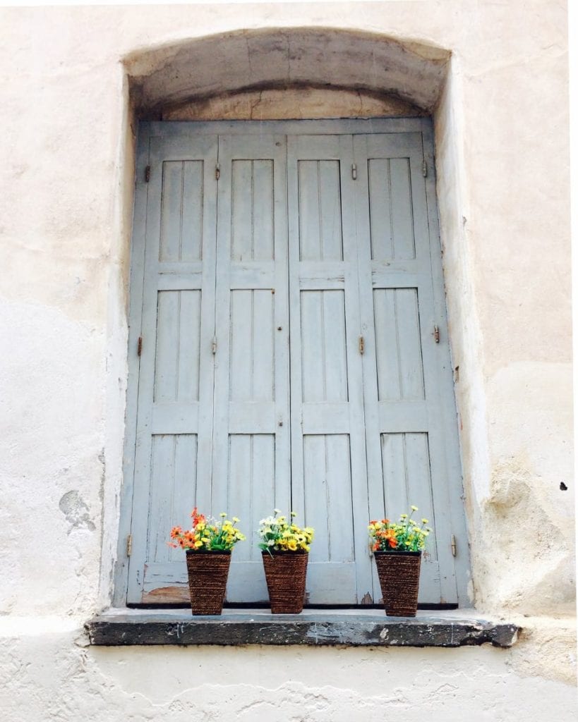 Image of window with blue shutters and flowers