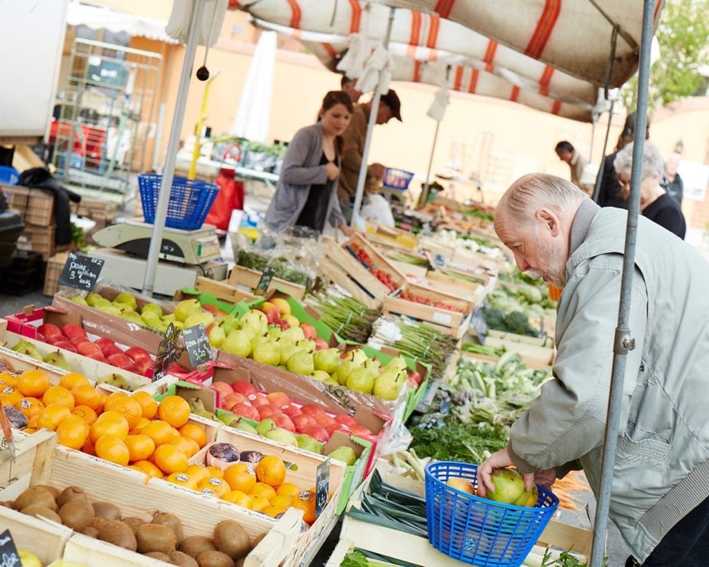 Image of old man buying produce at a market