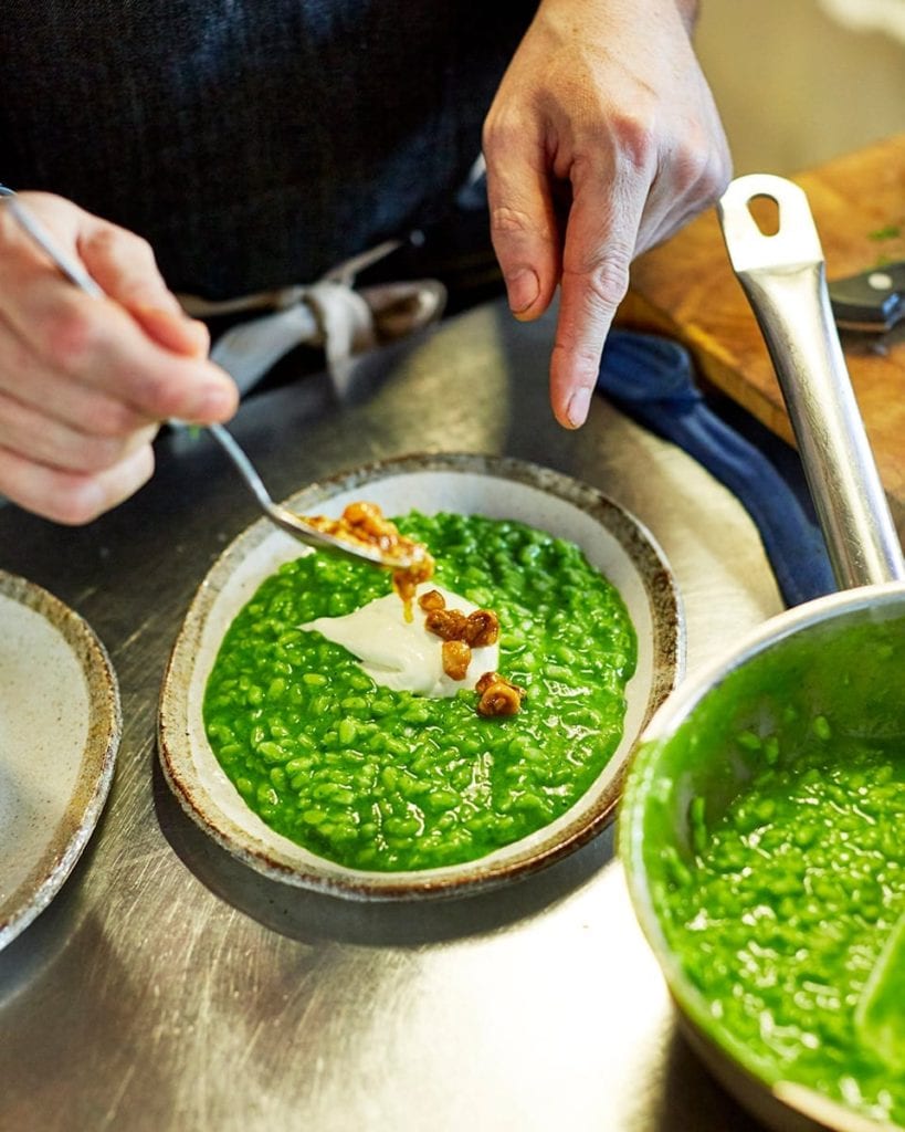 Image of bowls of vibrant green risotto topped with goat's cheese and nuts