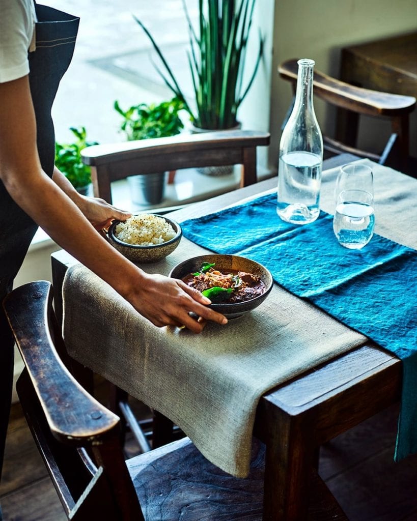 Image of a waiter placing massaman curry and rice on a table