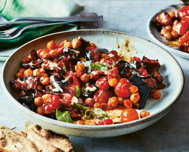 aubergine and chickpea traybake shown in a round blue bowl