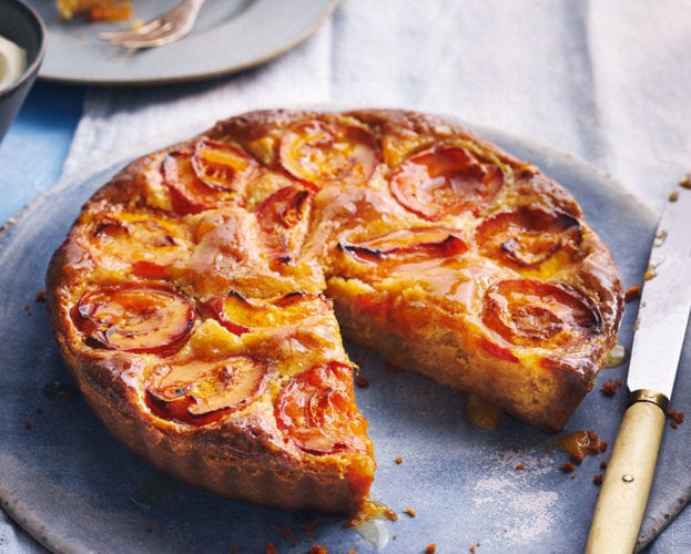 Apricot almond tart shown on a plate with a slice cut out