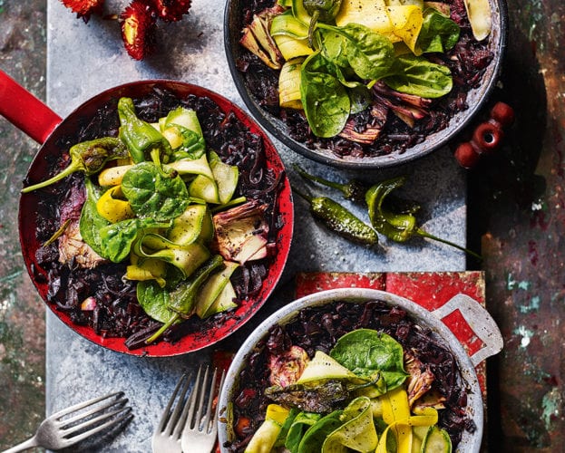 Black rice paella with artichokes, peppers and spinach