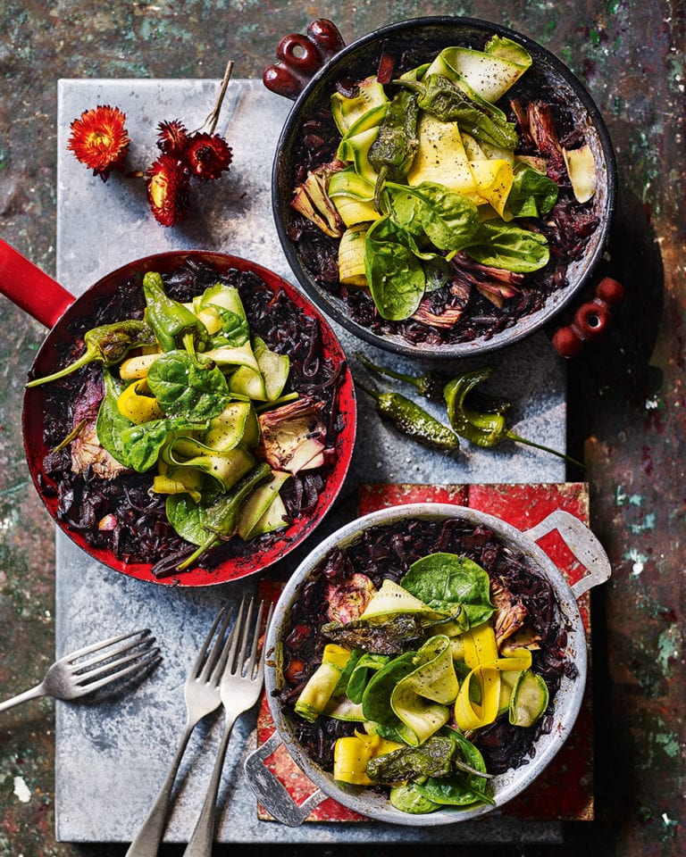 Black rice paella with artichokes, peppers and spinach