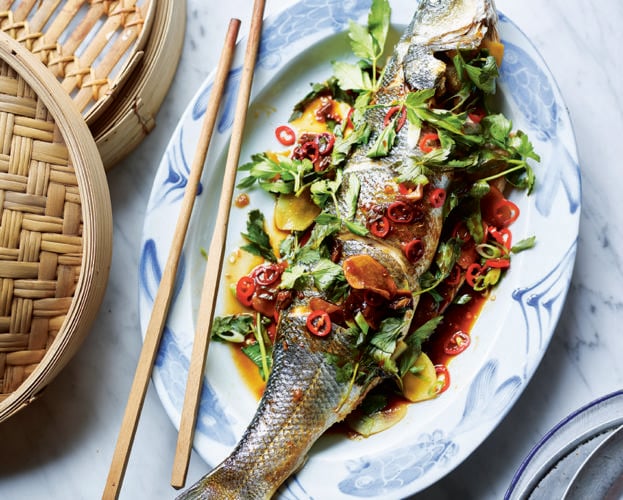Whole steamed fish shown on a plate with chopsticks