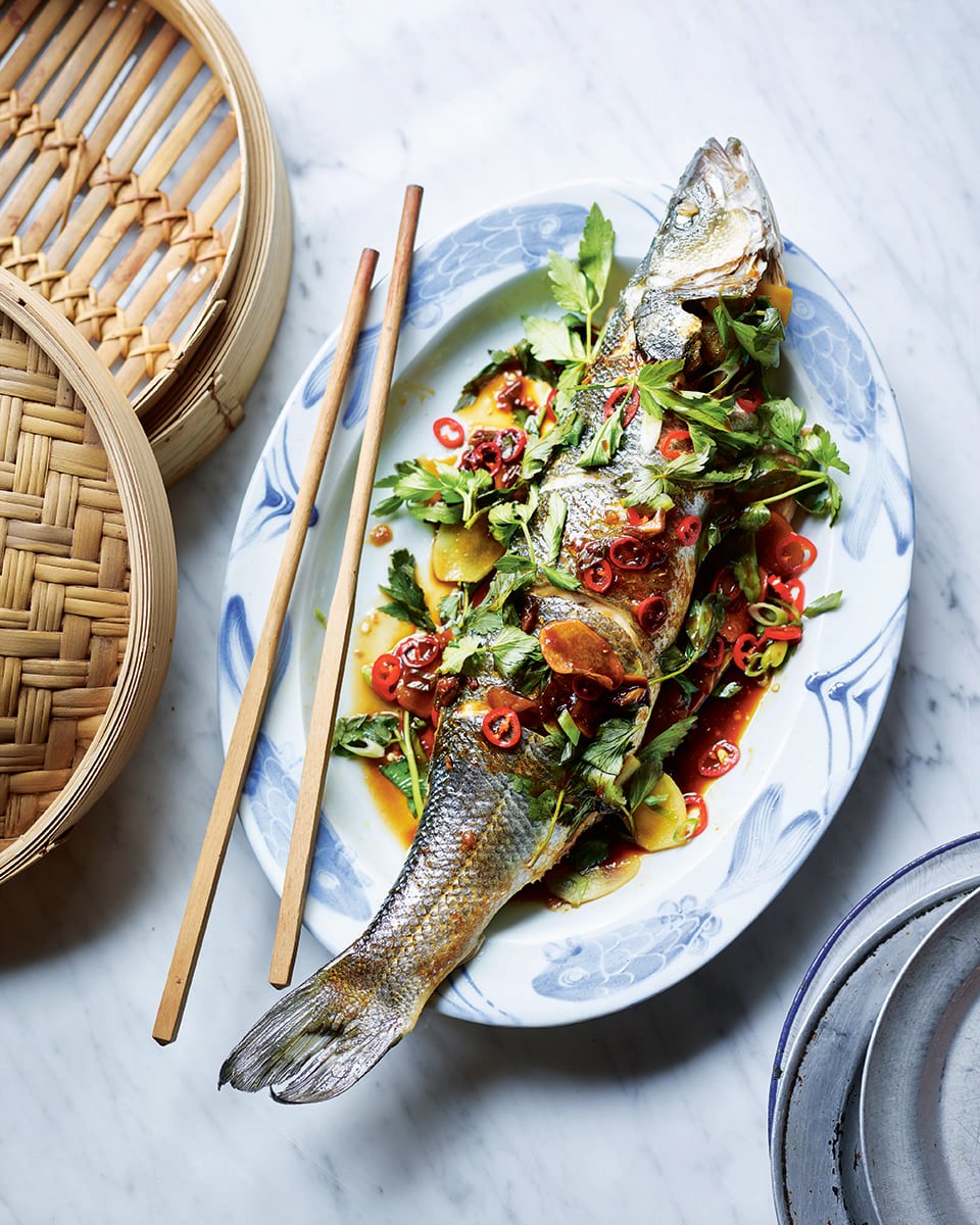 Whole steamed fish shown on a plate with chopsticks