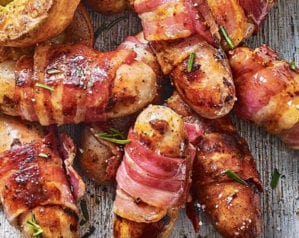 Pigs in blankets (sausages wrapped in bacon) shown on a wooden board