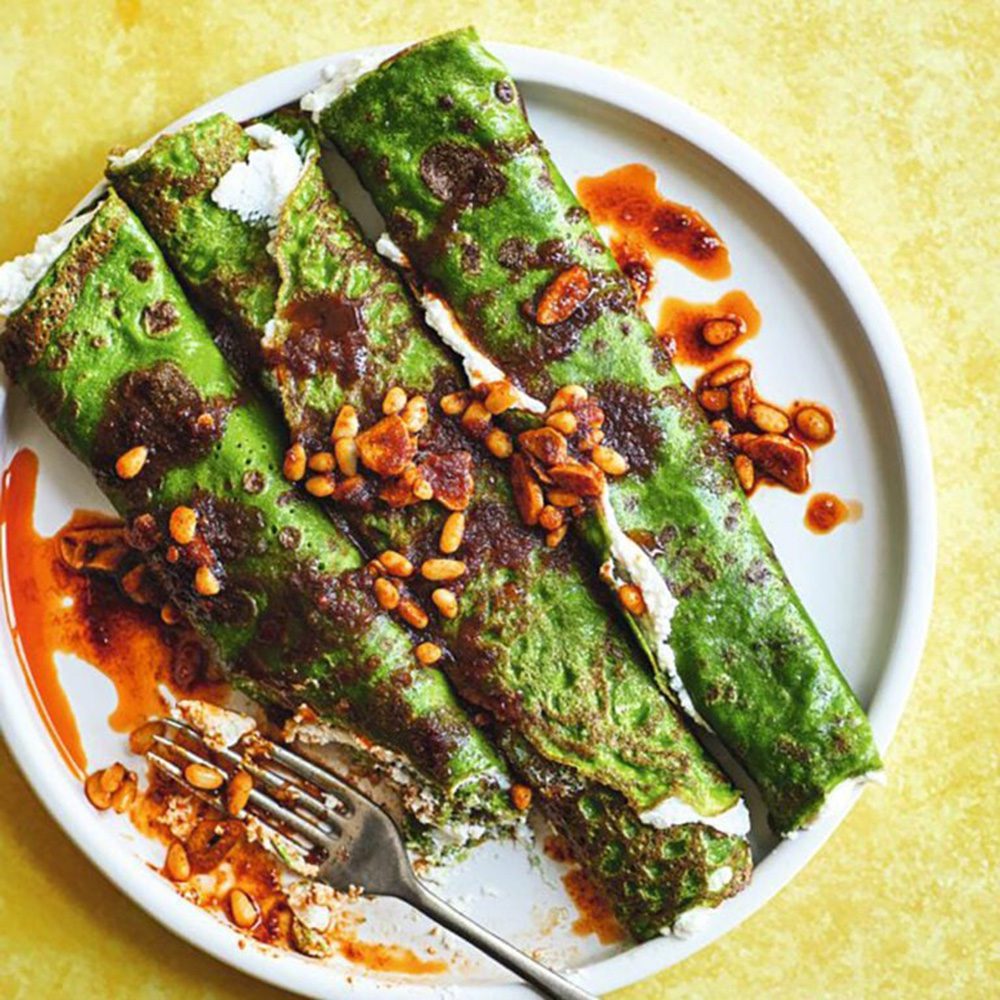 A plate of green pancakes drizzled with 'nduja oil