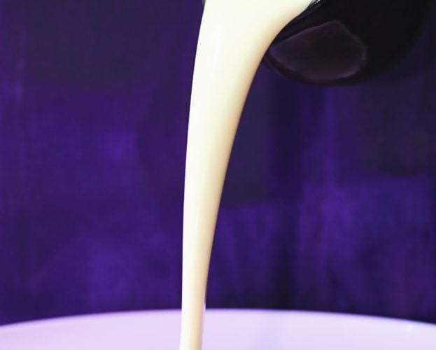 Creme anglaise being poured from a height onto a plate