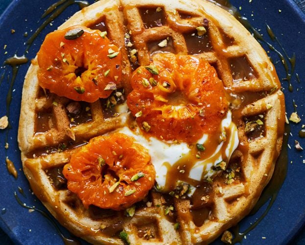 A waffle topped with clementines and caramel