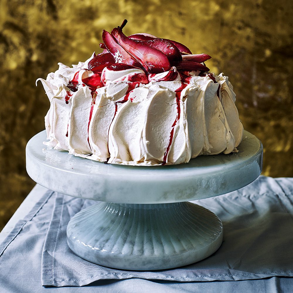 A large pavlova topped with red mulled pears