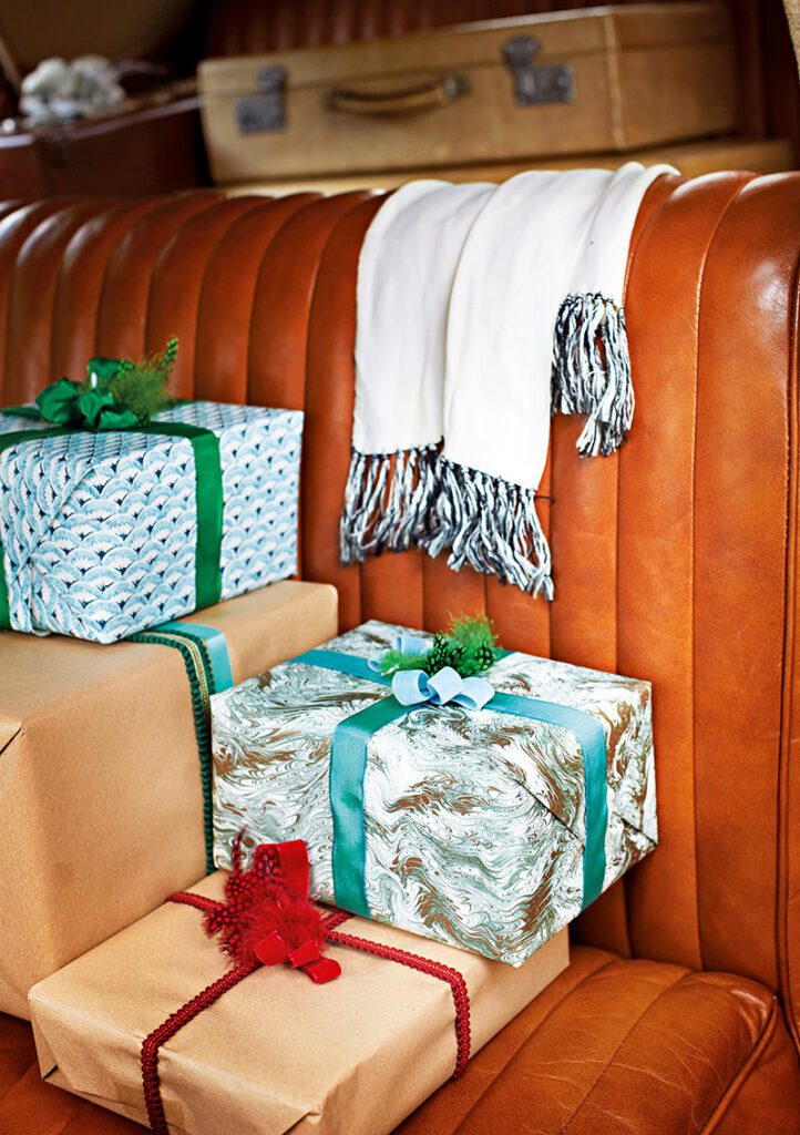 The backseat of a vintage car, loaded with gift-wrapped presents