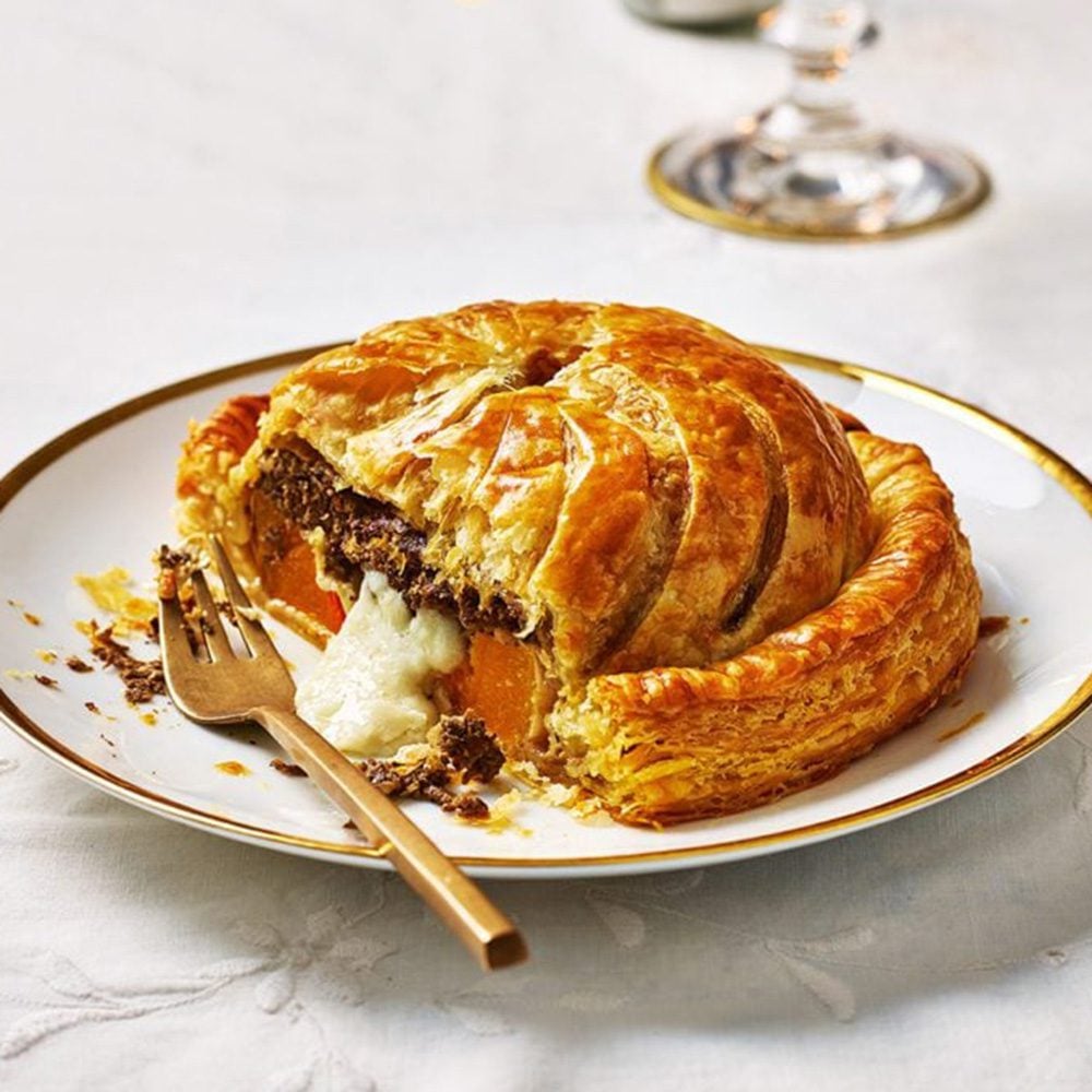 An individual pastry pithivier, sliced open to reveal cheese and squash